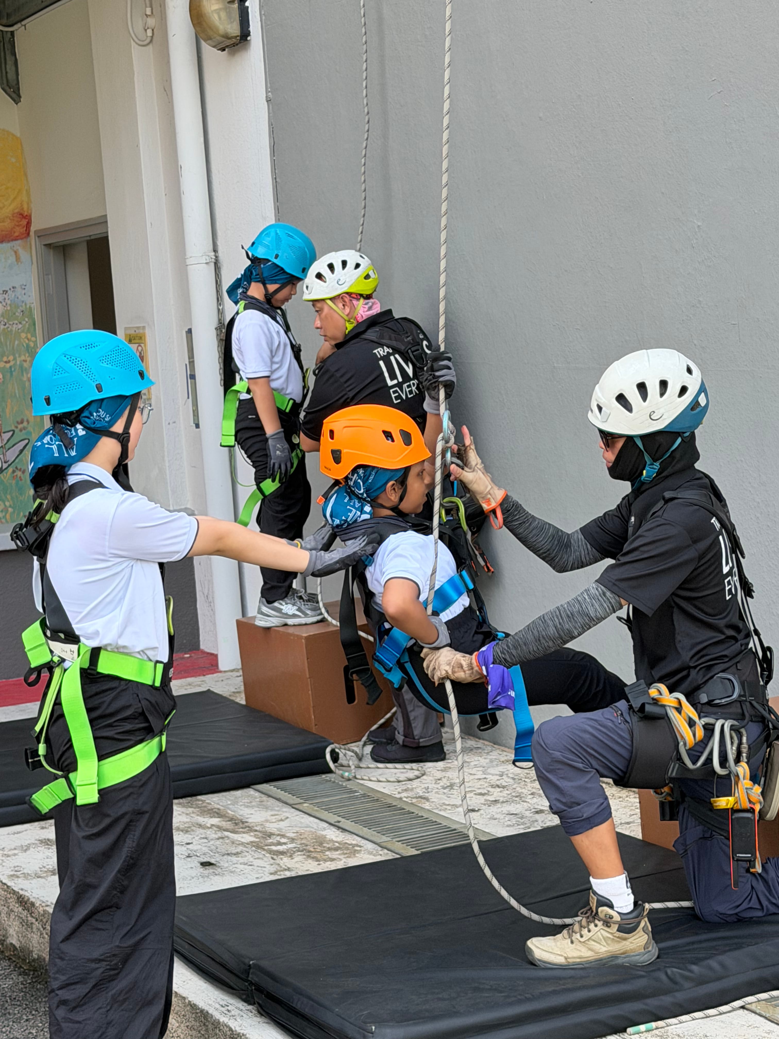 Getting ready to abseil, students and instructors work together to check gear and harnesses before the descent.